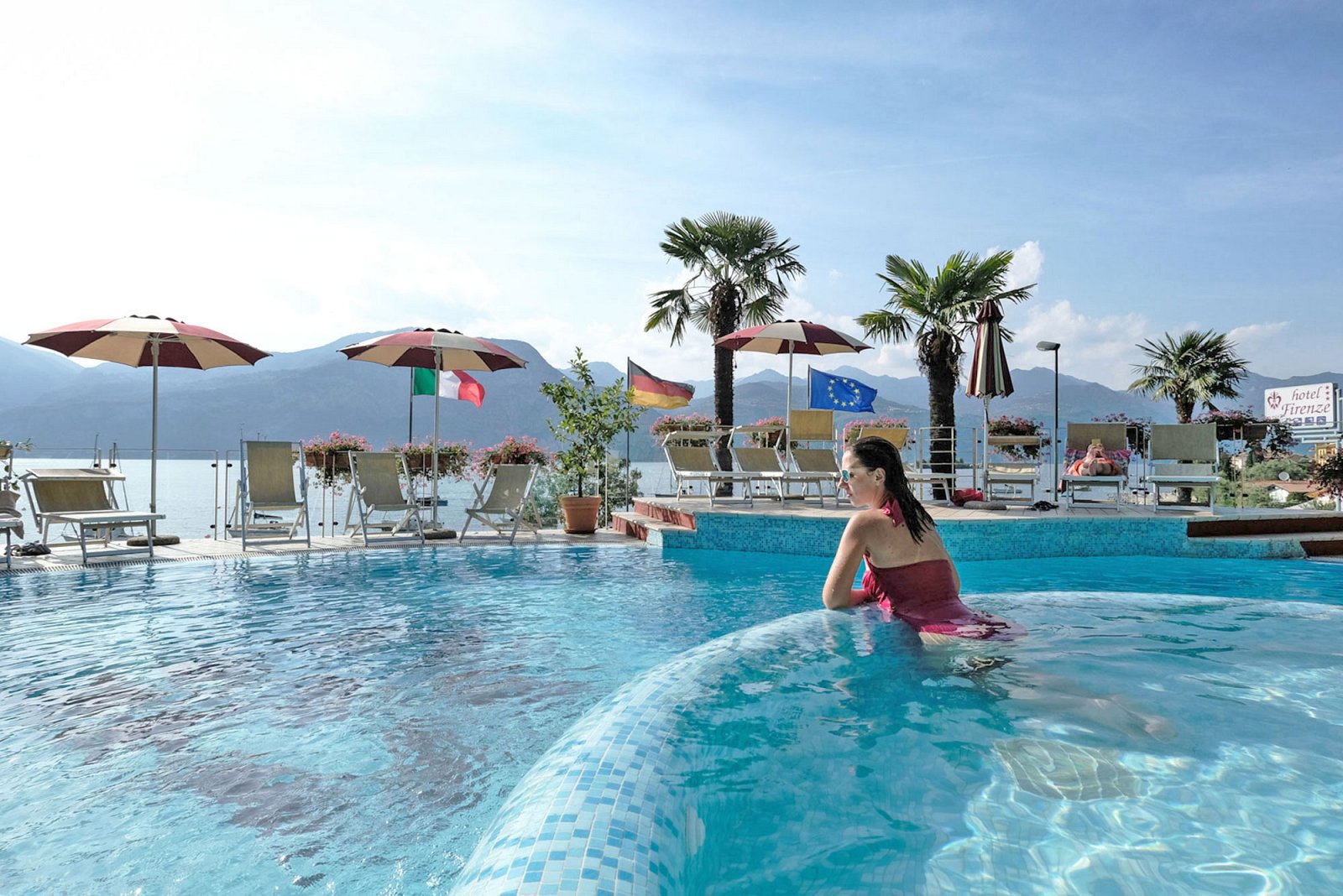 Mädchen entspannt sich im Pool mit Aussicht auf den Gardasee im 3 Sterne Hotel Firenze