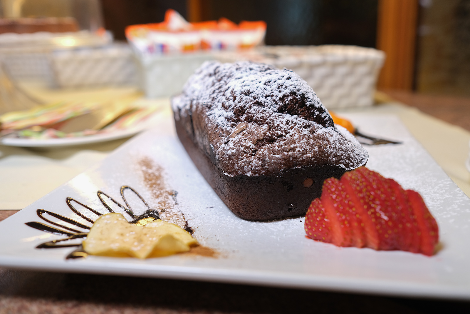 Schokoladenkuchen mit Puderzucker und Erdbeeren beim Frühstück im Hotel Firenze